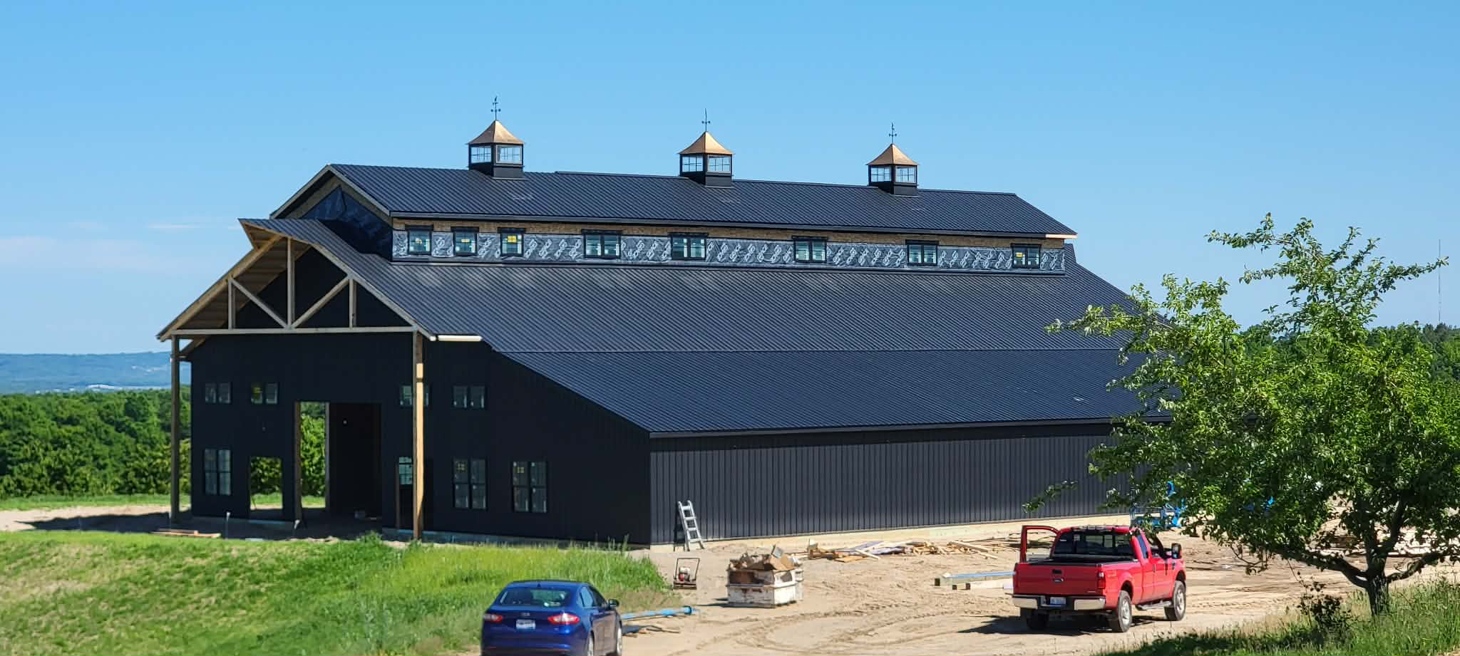 Dark-sided barn with timber framing and three cupolas overlooking the Northern Michigan landscape