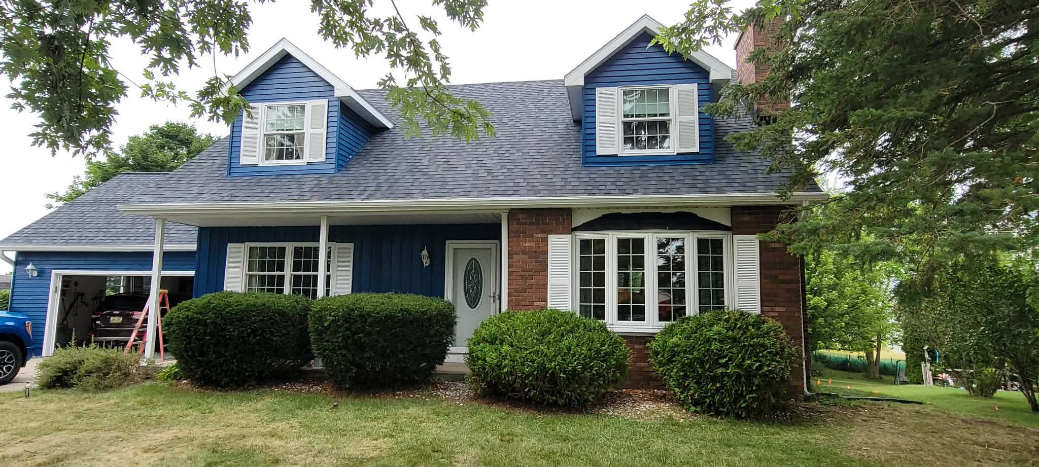 Blue two-story home with white shutters and brick accents