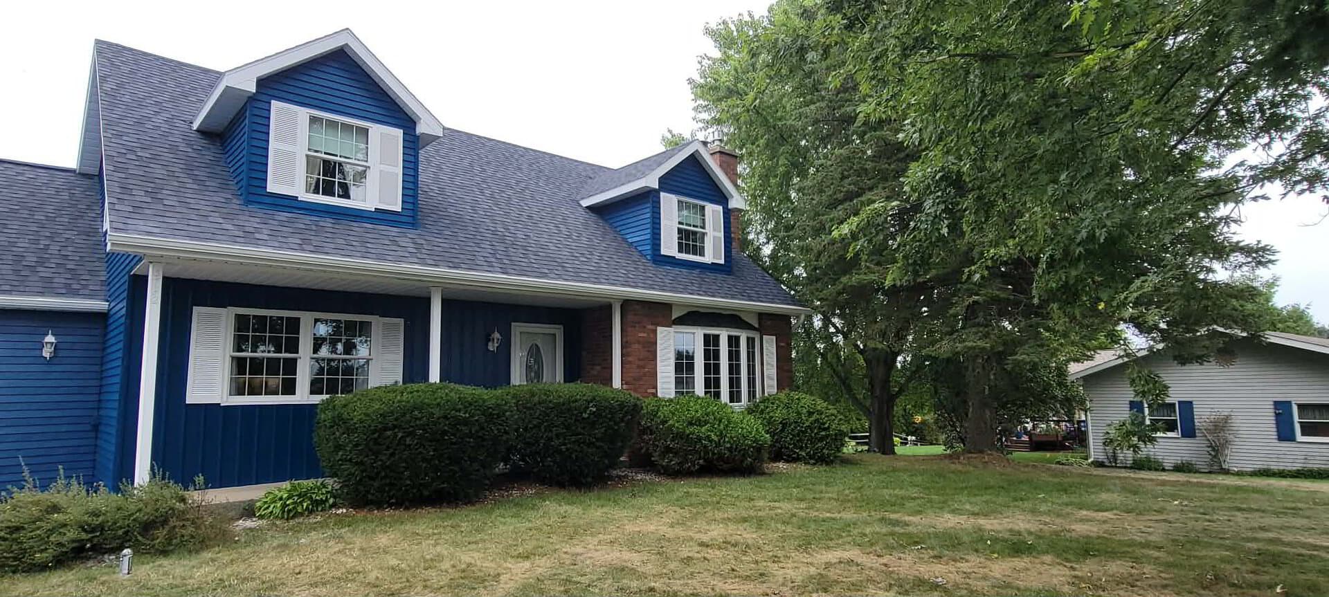The house with blue siding and crisp white trim after painting