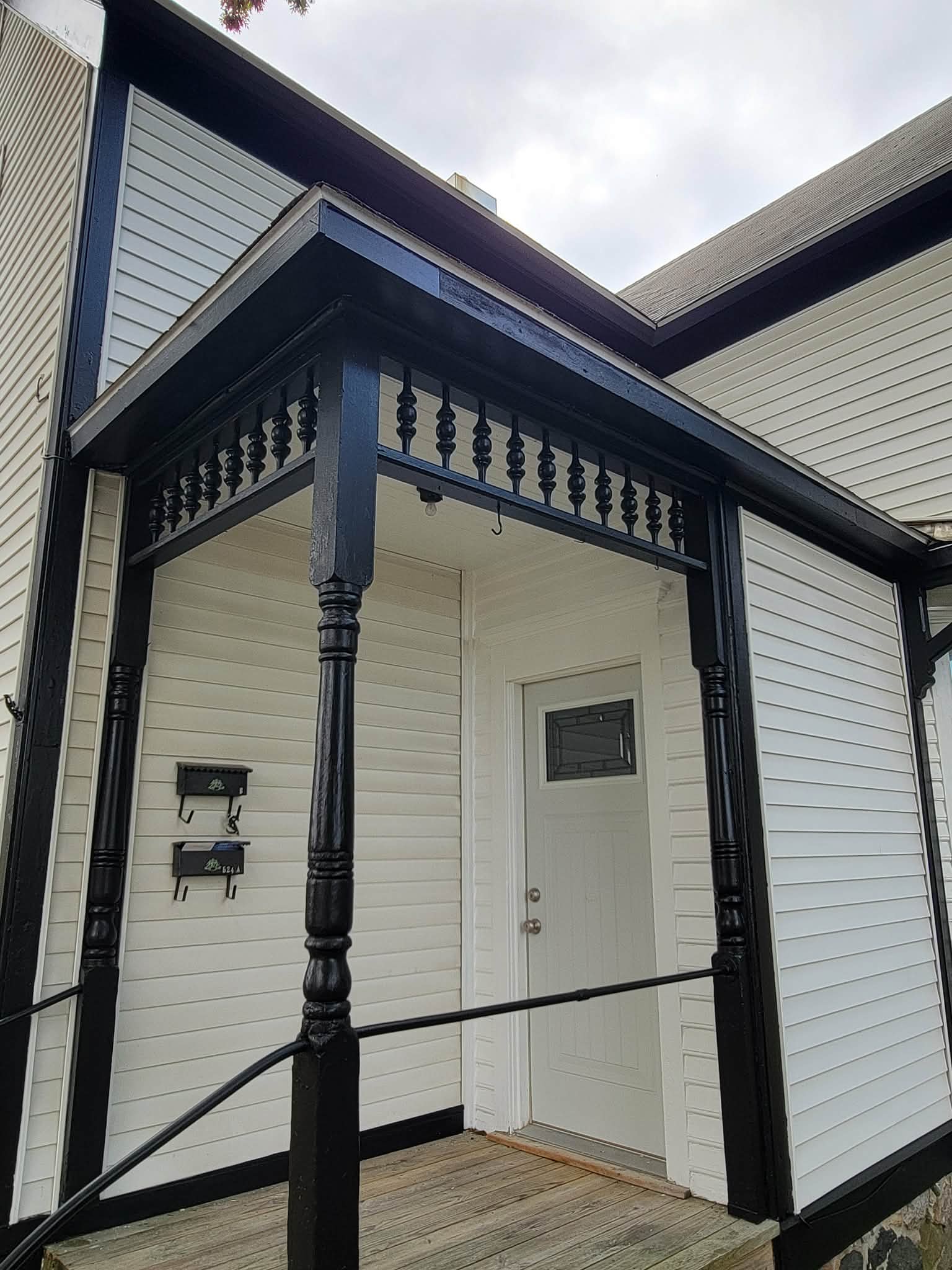 White porch with dark blue painted posts and decorative trim
